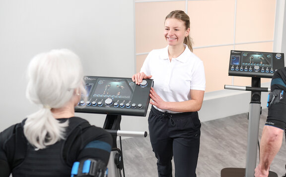Frau beim EMS-Training mit einer Trainerin mit Blick auf das Gerätedisplay Seite_Produkte_1_2026_02100172_2417x1500.jpg